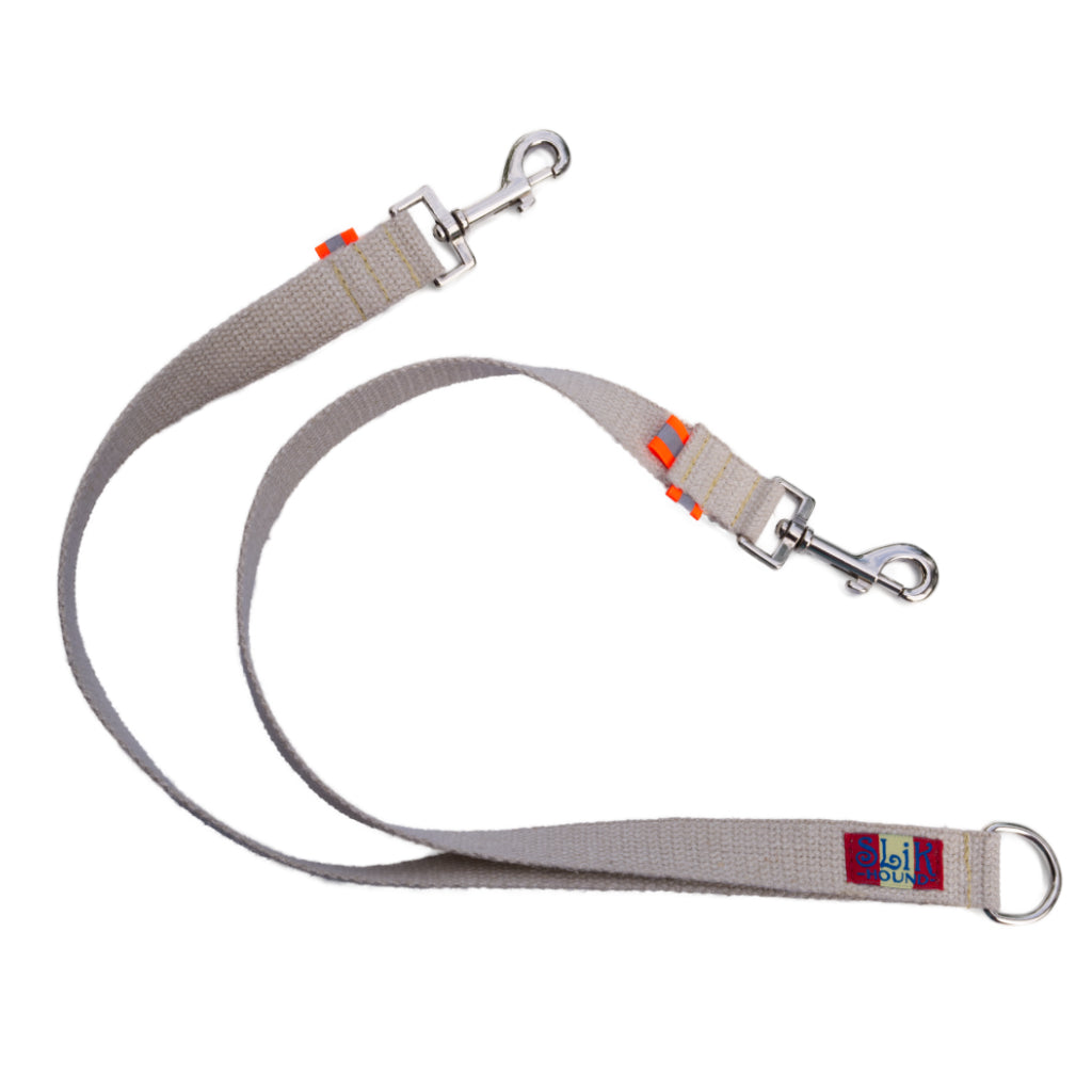 Tan undyed and nature hemp Canva leash splitter for dogs with fluorescent orange reflective tabs at all ends, yellow kevlar stitching and shiny silver metal hardware. pictured with white backdrop.