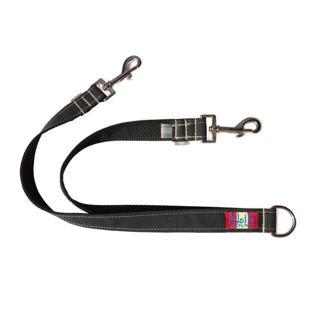black colored fabric wrapped leash splitter for dogs with shiny metal snap hooks and yellow kevlar stitching. Pictured against a white backdrop. Made by SLiK Hound
